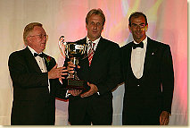 Don Panoz hands over the trophy for third place in the ALMS driver's championship to Frank Biela. Standing beside is Emanuele Pirro who achieved fourth place